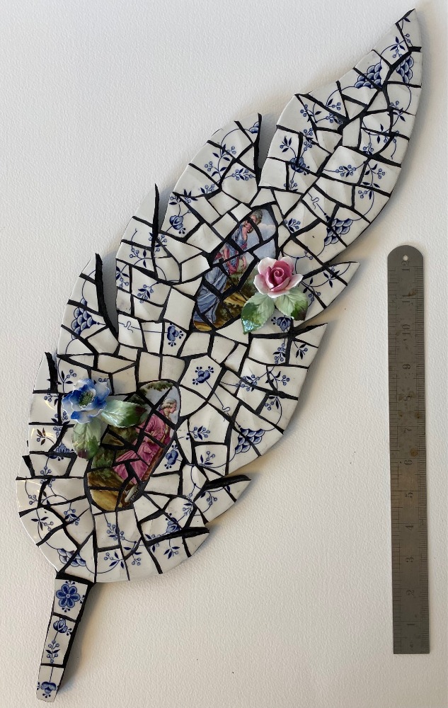 Mosaic feather is vintage crockery on cement board for indoors or outdoors. Vintage roses attached. Black grouting.