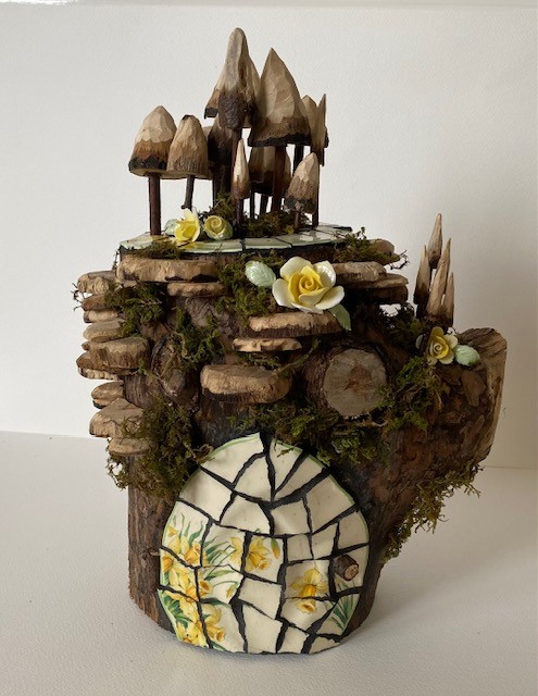 large log fairy house with hand carved toadstools and fungus with vintage roses.