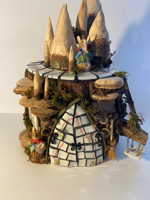 Large log Peter Rabbit style fairy house. log with hand carved mushrooms toadstools, fungus, Peter Rabbit plate mosaic door, twig ladder, ceramic swing on branch, Peter Rabbit figures