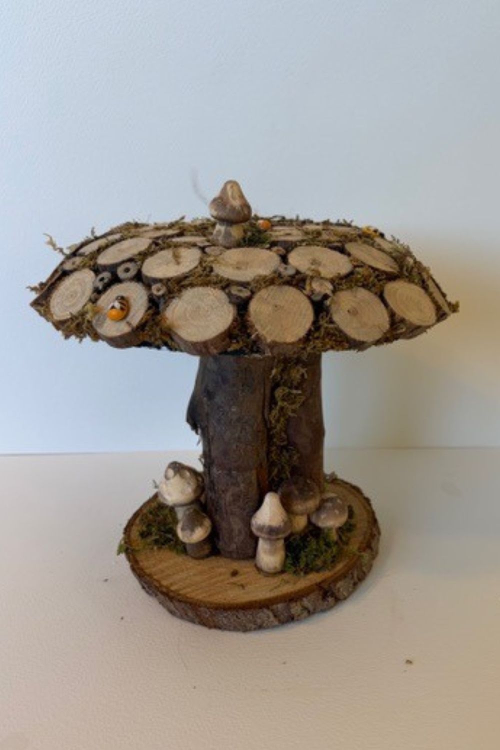This mushroom ornament is sculpted from an eco-conscious resin dome, The surface is carefully adorned with natural wooden log slices and preserved moss, creating rich texture and an authentic woodland feel. Set upon a solid log stem, the piece feels both grounded and sculptural—an elegant fusion of natural elements and contemporary craftsmanship. Each ornament is entirely unique, echoing the quiet beauty of the forest floor in a refined, decorative form.